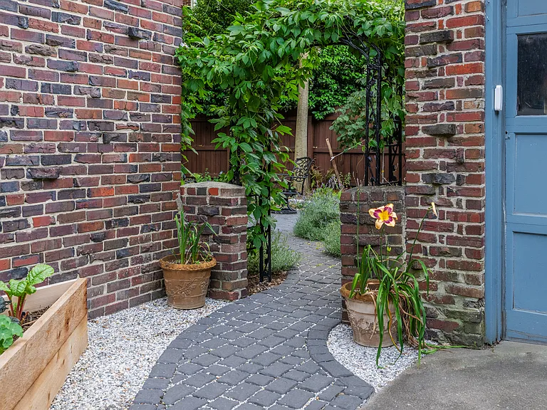 Meandering path to the backyard passes under an arbor adorned with native passionfruit.