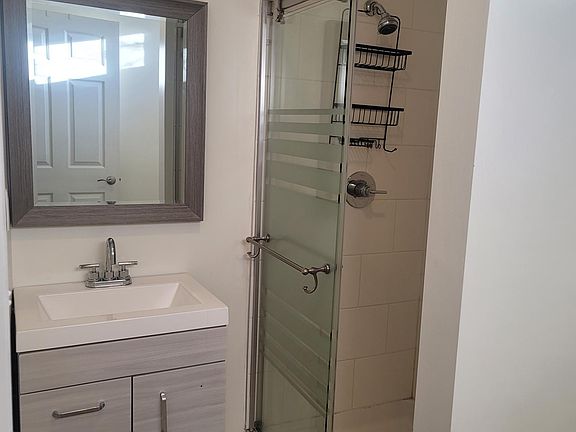 Beautifully tiled shower with modern vanity and flooring.
