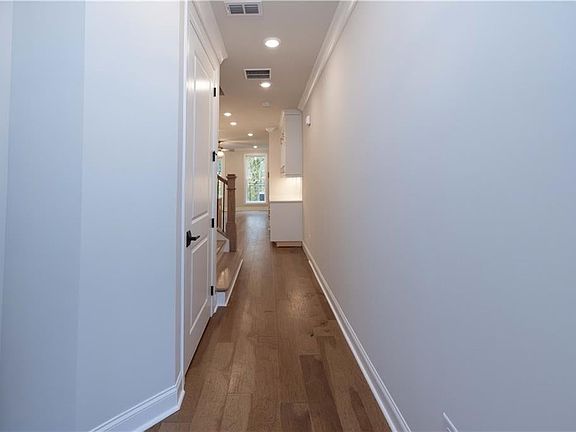 Hall with dark wood-style flooring, recessed lighting, and ornamental molding