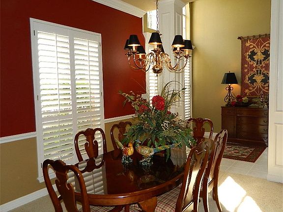 Warm formal dining area  features plantation shutters, crown moldings, and beautiful color tones.