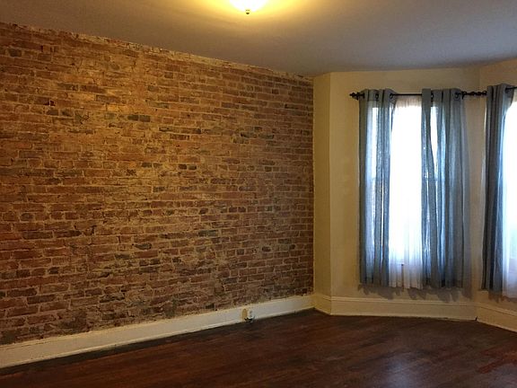 Large Living room is at the front of the apartment - sunlit with hardwood floors and brick wall reveal.
