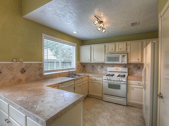 The kitchen features travertine counters and a stylish tumbled travertine backsplash and track light