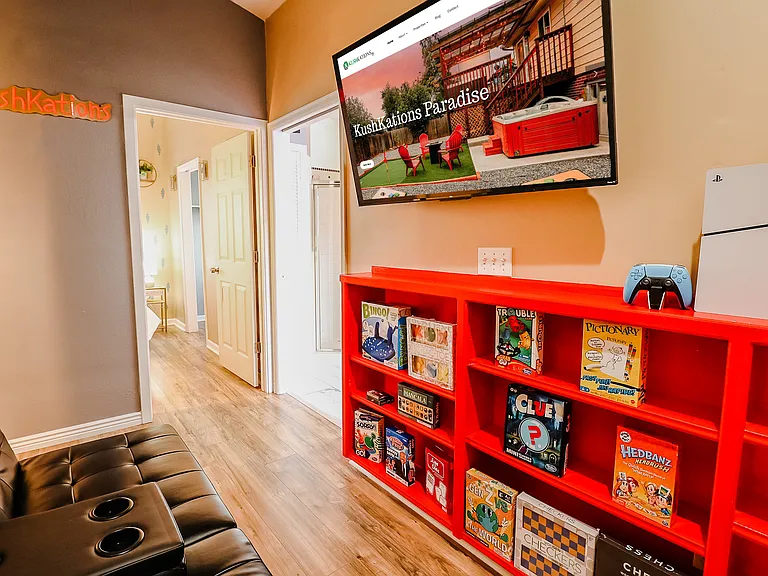 A vibrant setup featuring a TV atop a red cabinet, alongside a PS5 and a collection of board games, creating a colorful and engaging entertainment hub.