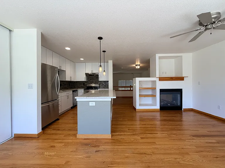 The updated kitchen includes white cabinetry, stainless steel appliances, modern countertops, a large center island, and stylish tile backsplash
