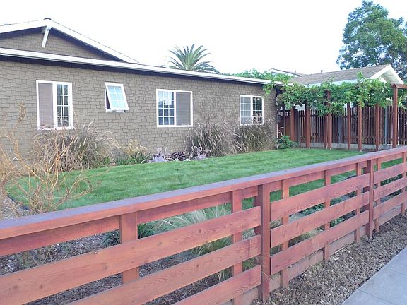 Front yard with fully enclosed fence, gate, and custom landscaping.