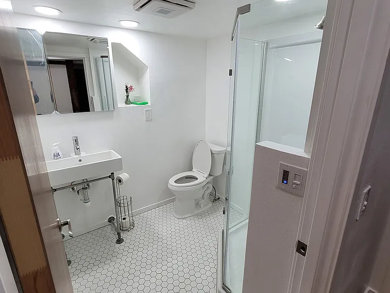 Modern bathroom with a glass shower unit and hexagon tiles.