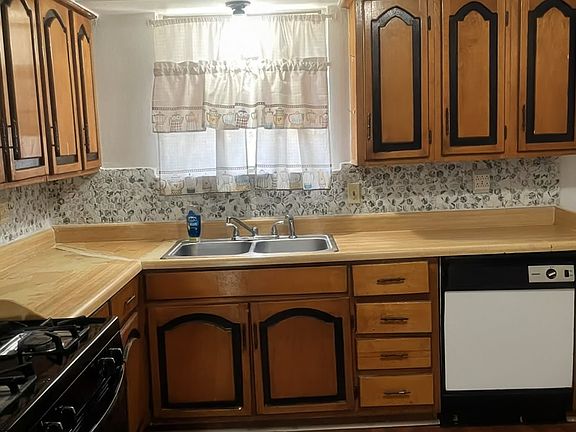 Functional kitchen with ample wood cabinetry, durable countertops, and a built-in dishwasher. Ready for home-cooked meals and entertaining.