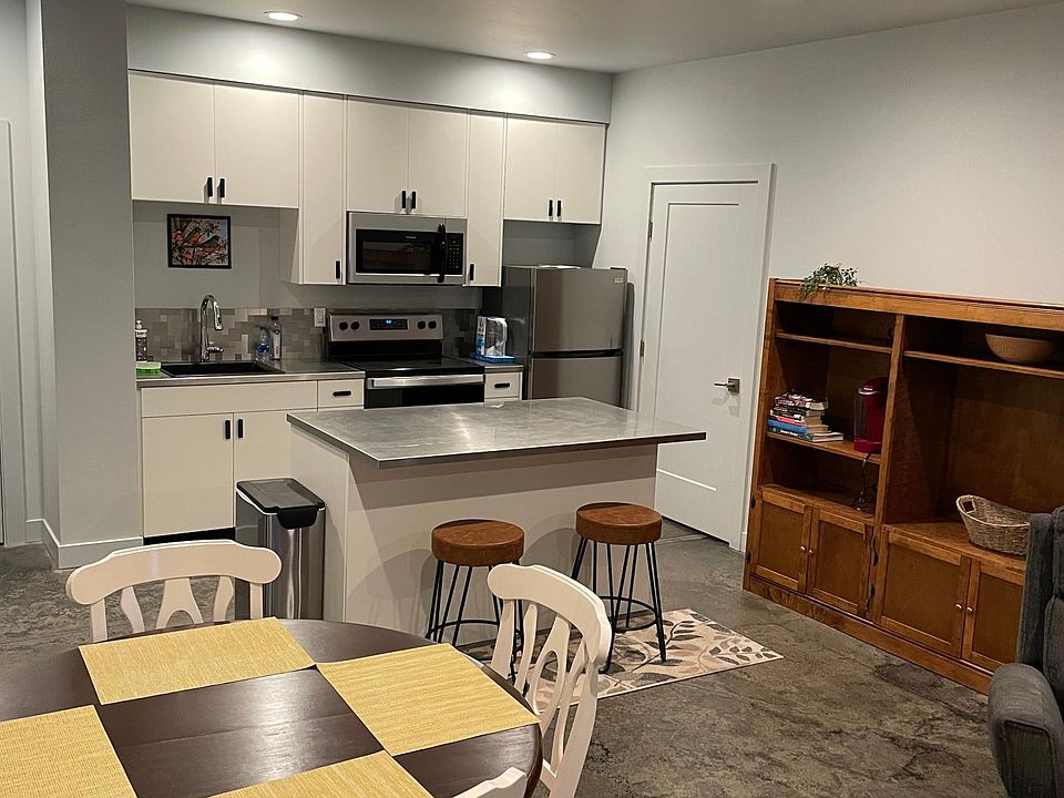 New kitchen with stainless steel counters, and bar seating, large storage unit to the right
