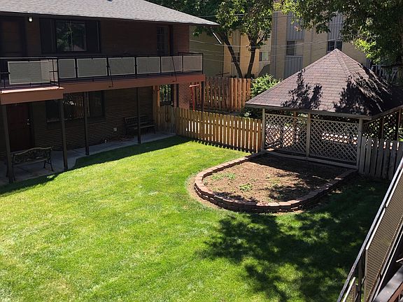 Charming backyard featuring lush green lawn, cozy wooden gazebo, and a spacious patio area perfect for outdoor relaxation.