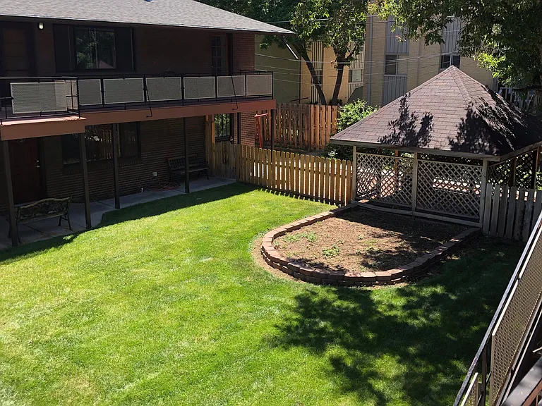 Charming backyard featuring lush green lawn, cozy wooden gazebo, and a spacious patio area perfect for outdoor relaxation.