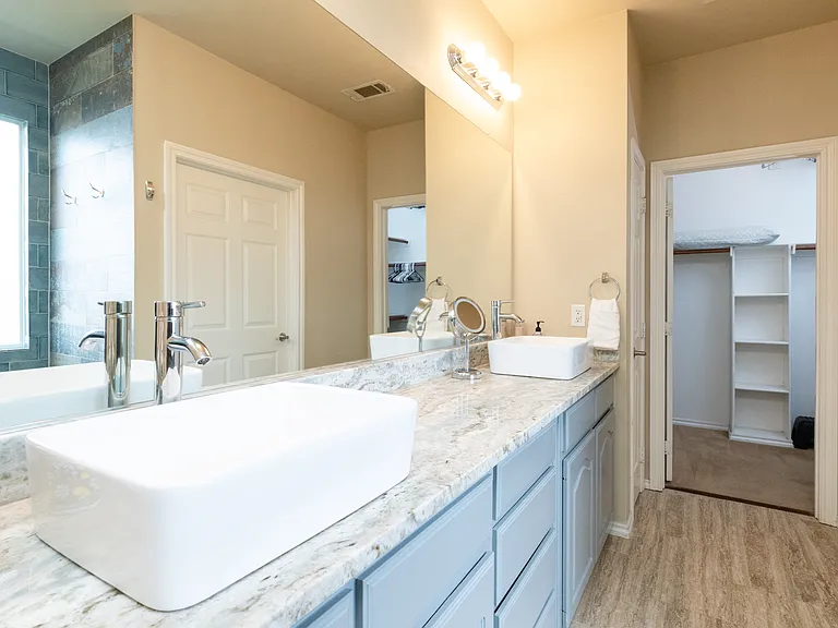 Spacious bathroom attached to the primary bedroom with double sinks, large mirror, and ample counter space. Convenient access to the walk-in closet. Bright, clean, and easy to get ready in.