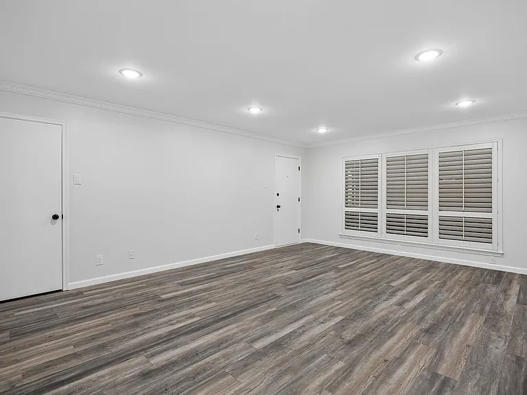Spacious room featuring wood-finish flooring, recessed lighting, crown molding, and plantation shutters