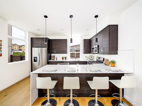 The kitchen has quartz counters and ton of cabinetry, stainless appliances and attractive tile backsplash.