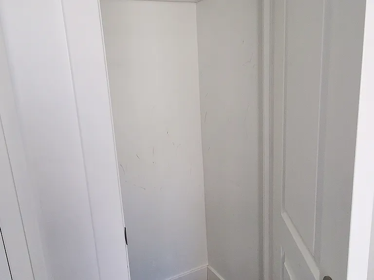 Dedicated closet space in the second bedroom, complete with a hanging rod and top shelf for organized storage.