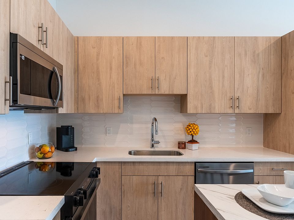 Modern kitchen with elegant wooden cabinets, stainless steel appliances, and a stylish quartz countertop.