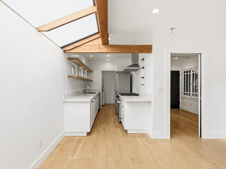 View of the kitchen (and laundry room past the kitchen) and bedroom from the Living room (under the skylight)