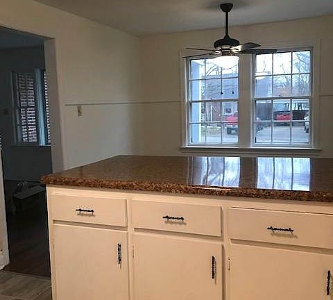 From the kitchen looking over the breakfast bar into the dining area. Kitchen/dining has great natural light and updated light fixtures with a ceiling fan fixture over the dining space.