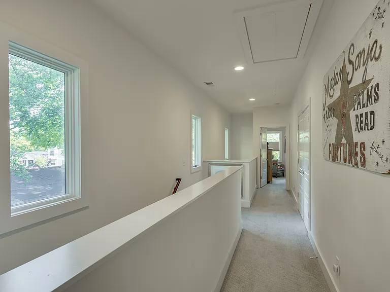 The second-floor hallway features soaring ceilings and large windows that fill the space with natural light, leading to two private ensuite bedrooms designed for comfort and relaxation.