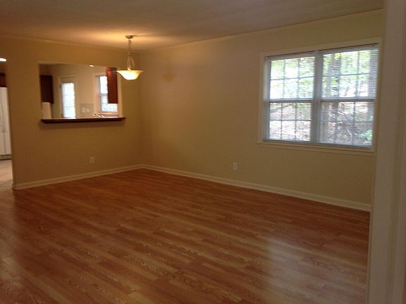 Living room showing second set of windows that view the woods in the back aswell as showing opening to kitchen.