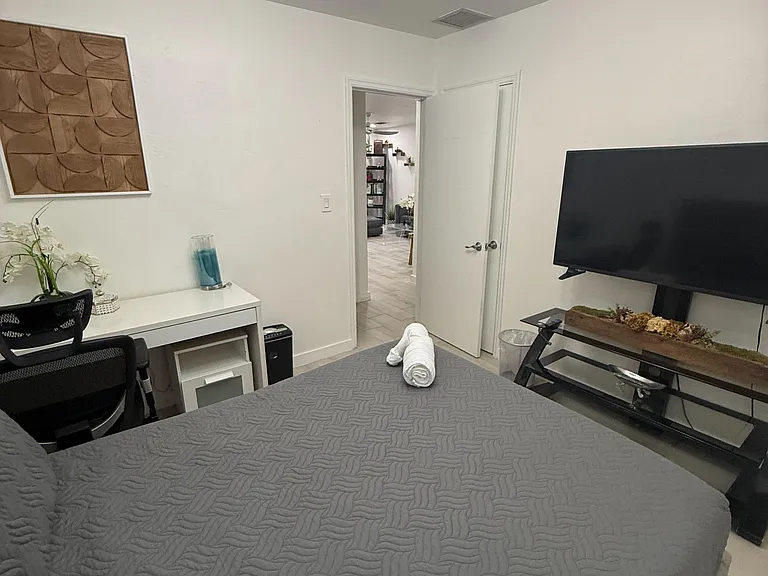 Furnished bedroom with a comfortable bed, work desk, and TV, plus easy access to the main living areas.