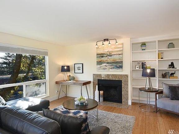 Living room with bamboo floors and wood-burning fireplace and built-in shelving.