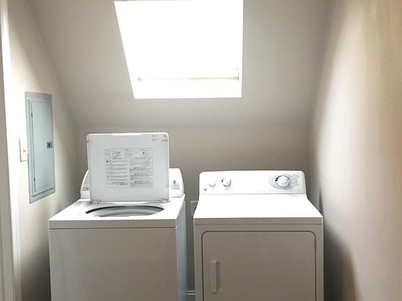 full sized washer and dryer area with skylight