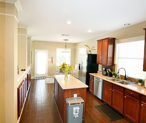 Kitchen with breakfast nook, wood-like tile flooring, stainless steel appliances.