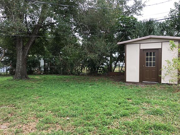 Large fenced backyard under shady trees, with spacious garden shed.