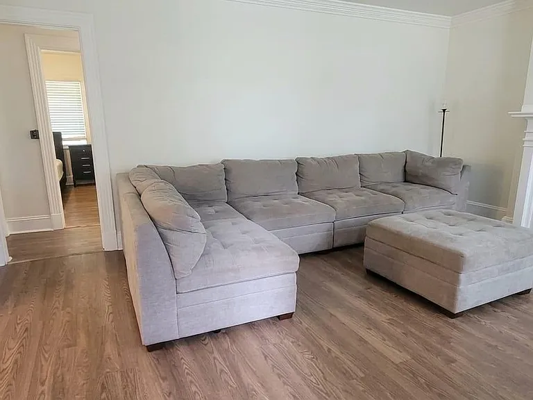 Spacious living room with large sectional seating, hardwood floors, and a decorative fireplaceideal for relaxing or hosting.