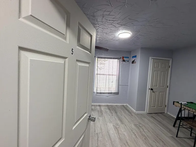 Private bedroom with wood-look flooring, a window with shades, and neutral walls with trim accents for easy furnishing.