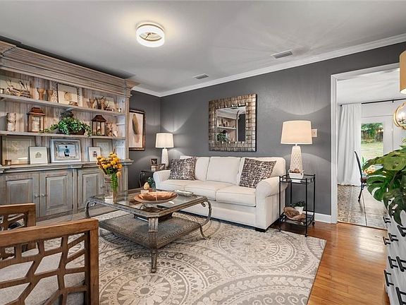Living room featuring ornamental molding, light hardwood / wood-style floors, and a chandelier