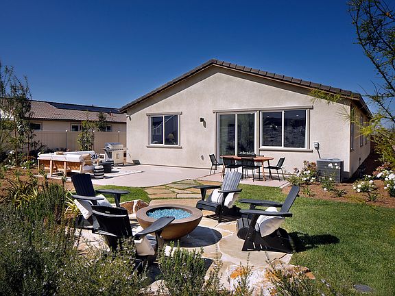 A cozy backyard with a patio set surrounded by lush greenery, against the backdrop of a well-maintai