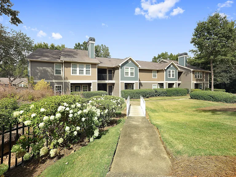 Building exterior with bushes, grass, and trees.