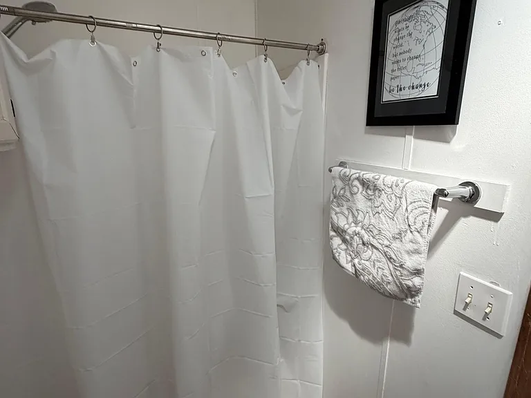 Full bathroom with shower/tub combo, curtain rod, towel bar, and easy-care flooring for everyday convenience.