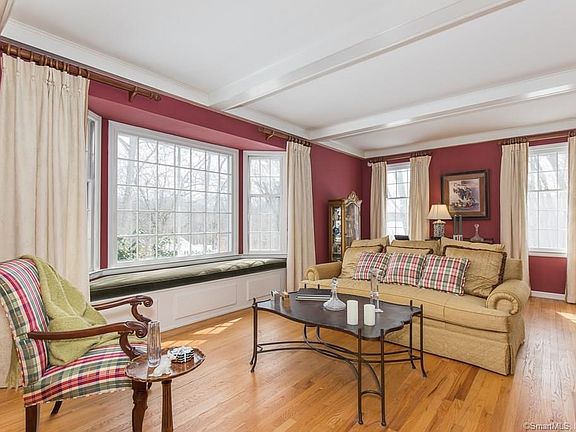 Living room is spacious with window seat, ceiling beams and fireplace.