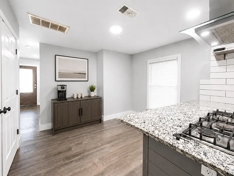 Kitchen features a large island with gas cooktop, stone-look counters, tile backsplash, and ample floor space.