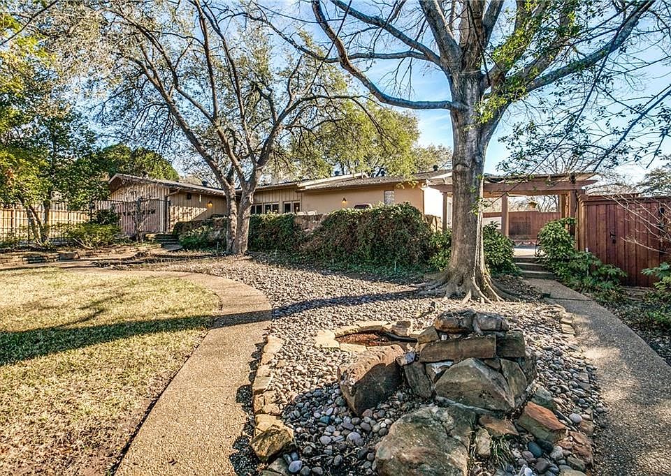 View of the back yard with pond, pergola, upper patio and patio by pool (far right). Metal fencing plus board on board fencing. Lush St. Augustine lawn.