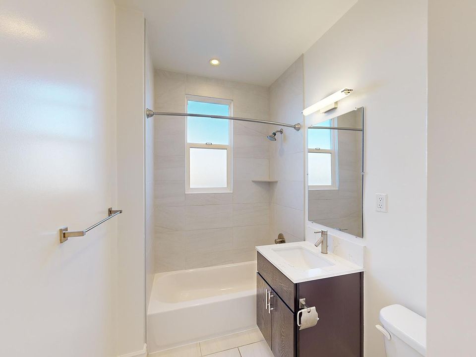 Modern bathroom featuring a bathtub, shower, sleek vanity with a sink, mirror, and bright windows