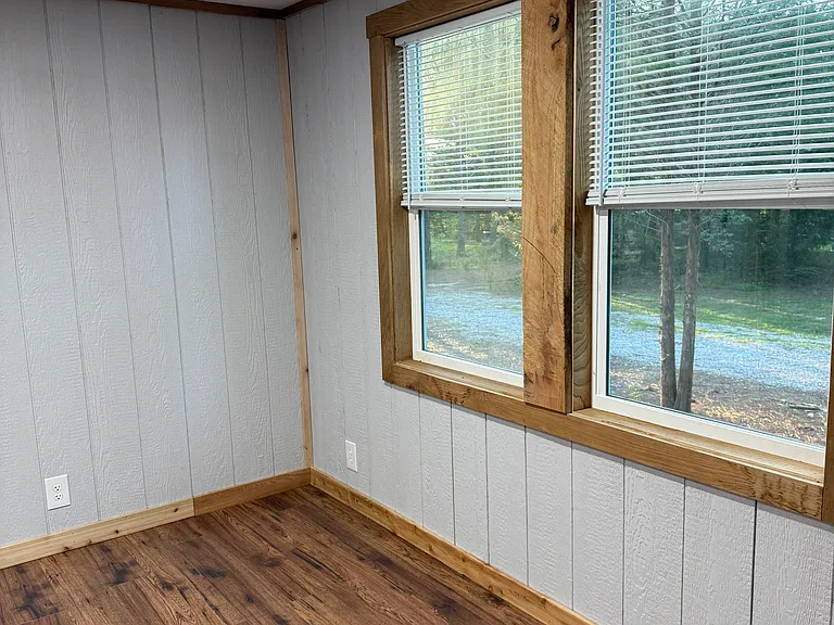 Master bedroom with double windows with cordless mini blinds, laminated hardwood floors with oak trim and mini split wall hung unit.