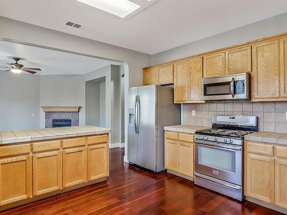 Kitchen featuring tile countertops, stainless steel appliances, and plenty of cabinet storage.