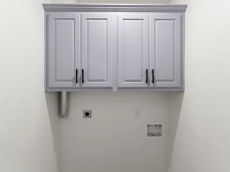Laundry space featuring light gray upper cabinetry with crown molding and matte black hardware