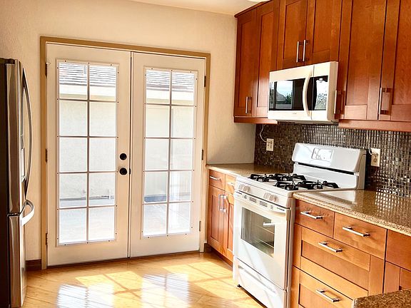 Light and bright kitchen with custom cabinetry, granite counters, french doors to private outdoor space