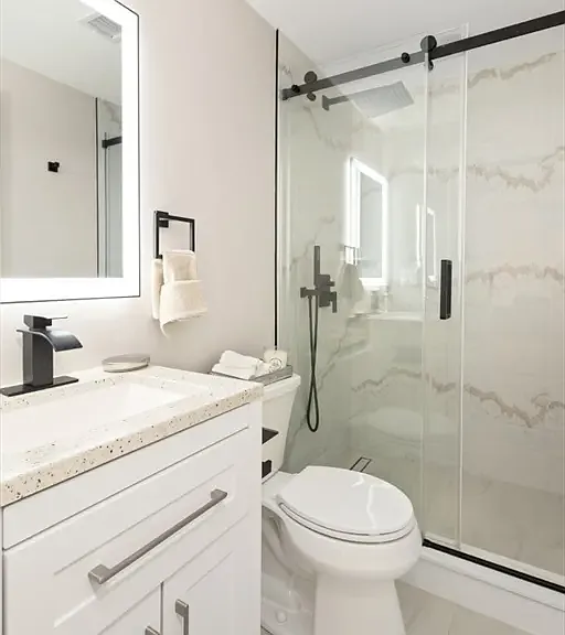Modern convenience: A shared full bathroom featuring a sparkling standing shower with premium glass doors.