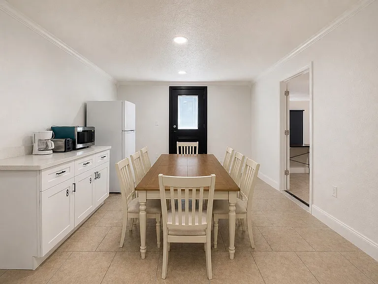 Dining area with a full-size table, microwave, toaster, coffee maker access to the adjacent kitchen and outdoor patio area.