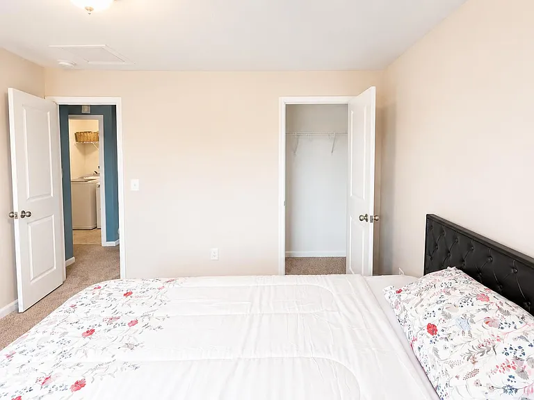 Spacious bedroom with plush carpeting, a comfortable bed setup, and a walk-in closet with shelving for easy storage.