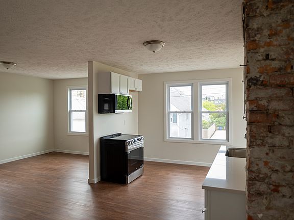 Brick accent wall leading into kitchen. Refrigerator is not shown but is included and installed.