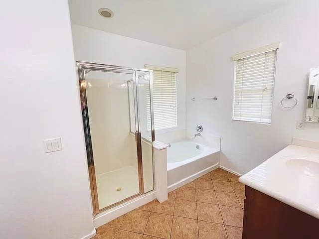 Master bath with double sink and separate shower and tub as well as private toilet room