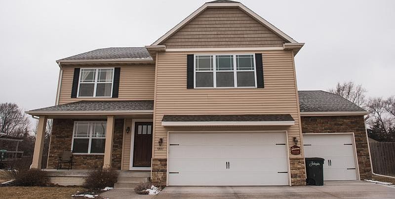 Front of house, large driveway with basketball hoop