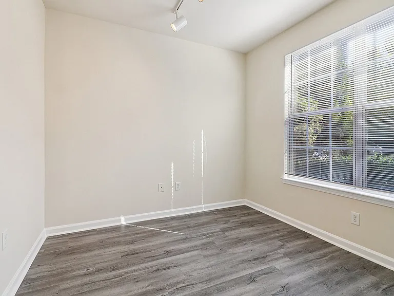 Bright room with sleek hardwood floors and large window offering ample natural light.
