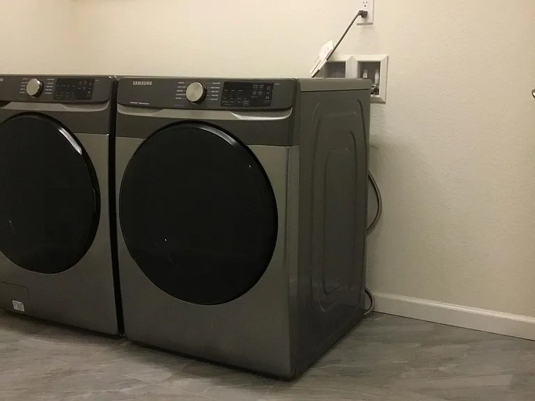 Front load Washer and Dryer in spacious laundry room with shelves and hang up area